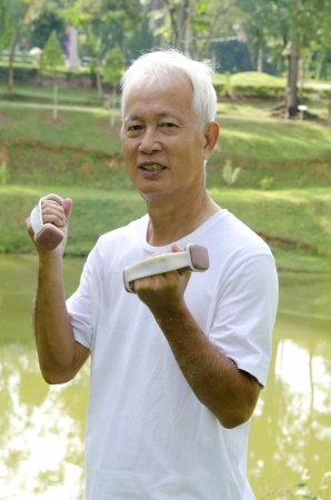 Senior man using dumbells on outdoorの写真素材