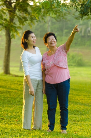 happy asian mother and her daughter, pointed and looking at somewhereの写真素材