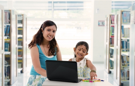 mother and daughter with laptop learning inside a library, indian south asian peopleの写真素材
