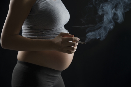 Smoker pregnant mother on a over dramatic dark lightの写真素材