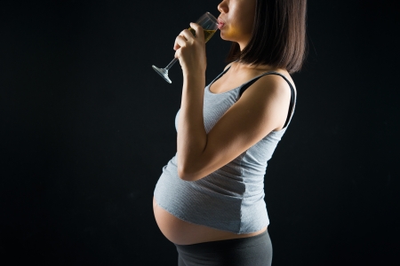 drinking pregnant mother on a over dramatic dark light backgroundの写真素材