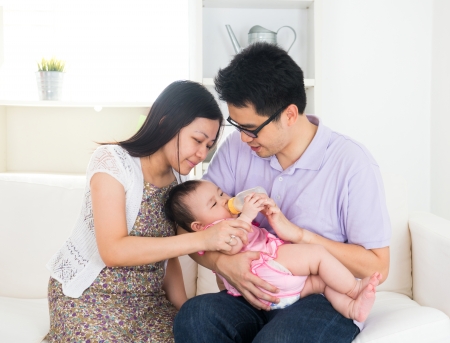 asian parents feeding baby boy at homeの写真素材
