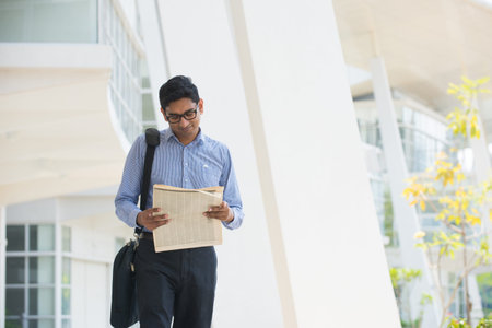 indian business male reading paper and walking 