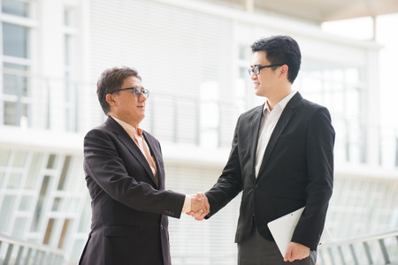 asian business handshake between senior and young business maleの写真素材