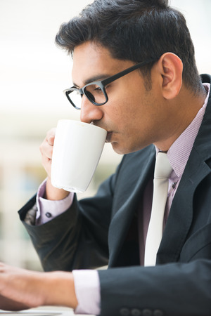close up of young indian business man enjoying coffe during workの写真素材