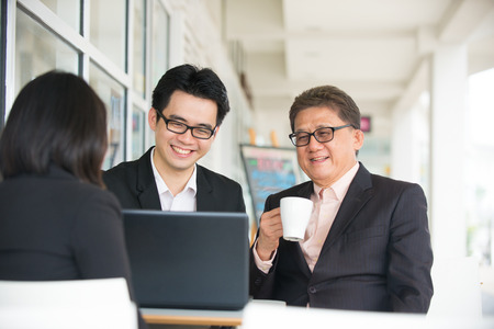 Group of  asian business people gathered together at a table discussing an interesting idea in the cafeの写真素材