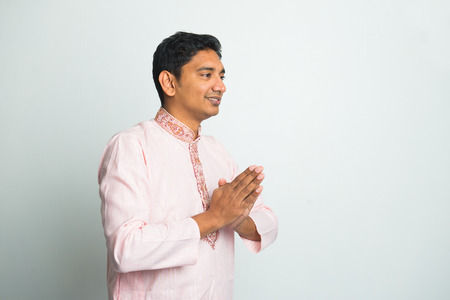 young indian male with Pranamasana greetings sign on traditional dress with plain background

の写真素材