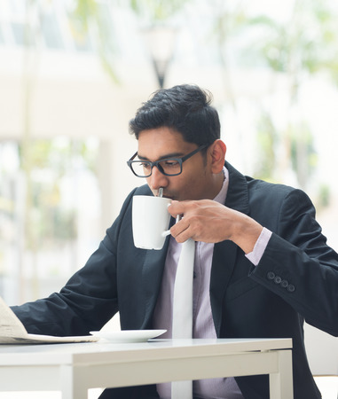 indian business male with newspaper and coffee at a cafeの写真素材