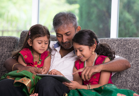 indian father with his daughter using a tablet computer on living roomの写真素材