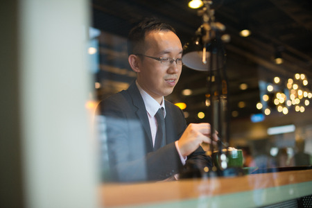 asian business man having coffee in cafe, hong kongの写真素材