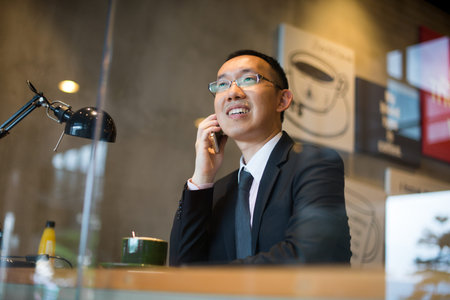 asian business man having coffee and phone conversation at cafe, hong kong