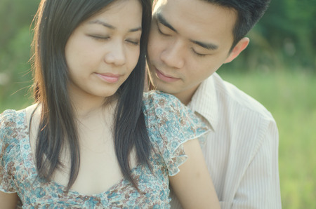chinese young couple embracing each other on meadowの写真素材