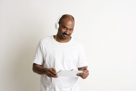 casual indian male on jeans and shirt and a tablet