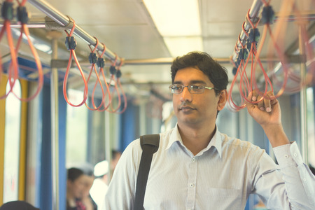 Asian Indian business man taking ride to work, standing inside train. Asian Indian business man taking ride to work, standing inside train.