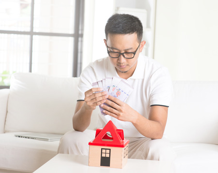 asian male thinking hard on mortagae at his homeの写真素材