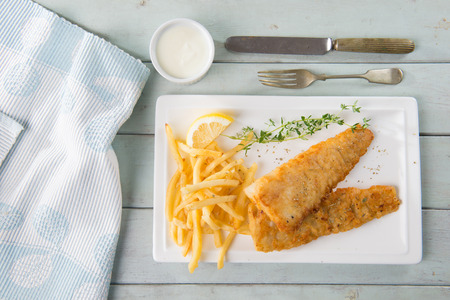 Fish and chips. Fried fish fillet with french fries wrapped by paper cone, on wooden background. Fresh cooked with hot smoke.の写真素材