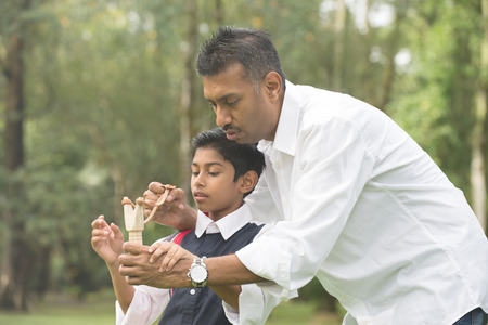indian father and son playing slingshot at the parkの写真素材
