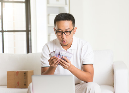 asian man earning cash from Internetの写真素材