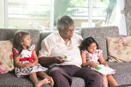 indian grandfather learning with his granddaughtersの写真素材