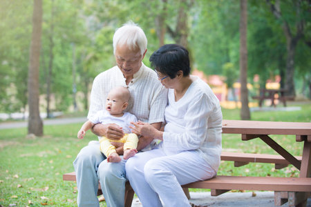 chinese grandfather and grandmother playing with baby grandson at outdoor