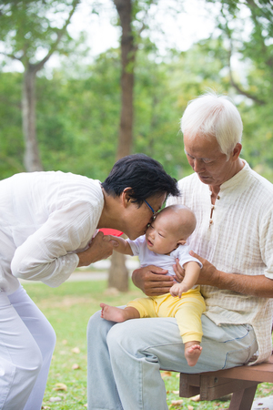 chinese grandfather and grandmother playing with baby grandson at outdoorの写真素材