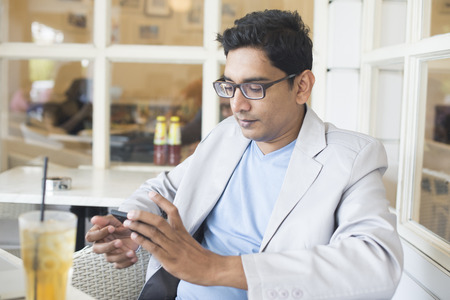 indian male drinking with laptop and phoneの写真素材
