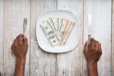 eating banknotes symbolising consumerism and corruptionの写真素材