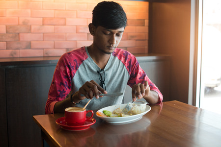 teenage indian male eating at cafeの写真素材