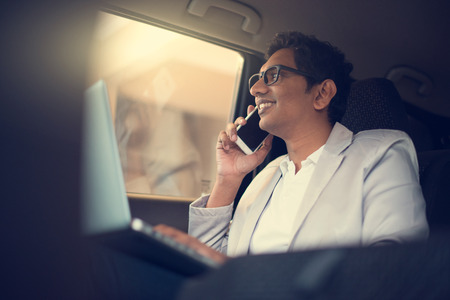 indian business male using laptop and phone inside the carの写真素材