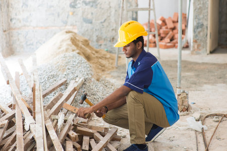 indian male contractor on site using hammer