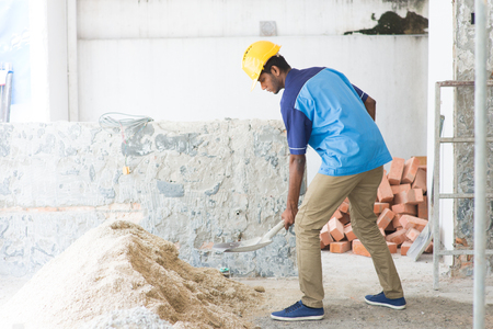 indian male contractor using shovelの写真素材