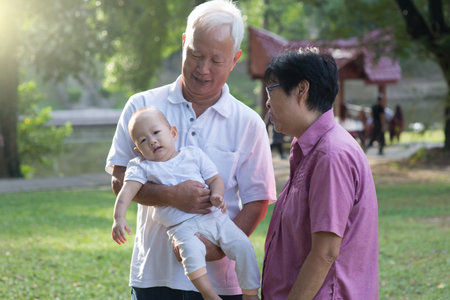 Chinese Grandparents Giving Granddaughter Ride On Shoulders