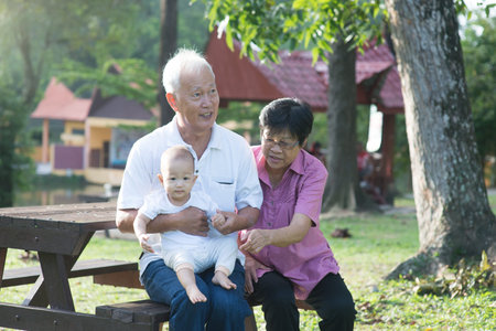 Chinese Grandparents Giving Granddaughter Ride On Shoulders