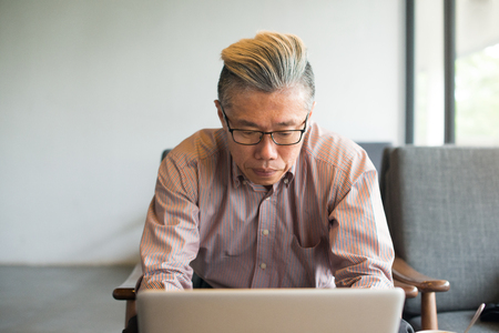 asian senior male using laptop on cafeの写真素材