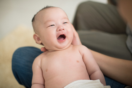 cute looking asian baby being held by fatherの写真素材
