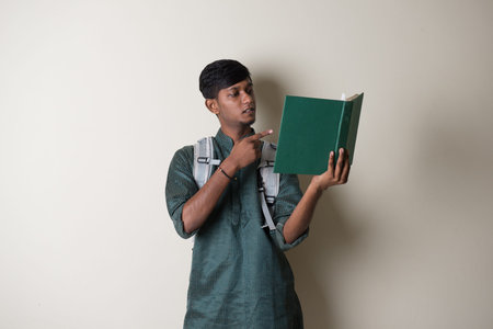 teenage indian male in traditional dress reading booksの写真素材