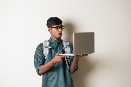 teenage indian male in traditional dress with laptopの写真素材