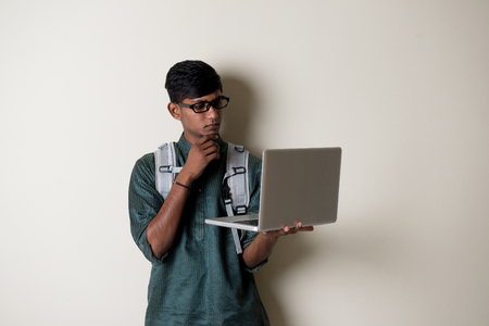 teenage indian male in traditional dress with laptopの写真素材