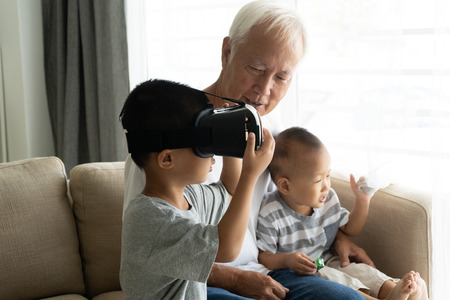 asian boy using VR goggles with grandparent technology photoの写真素材