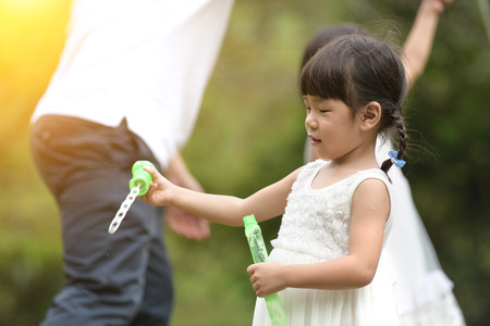 asian girl playing soap bubbles outdoorの写真素材