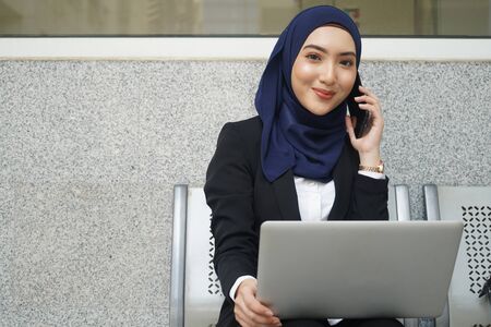 Attractive female muslim woman on a laptop and phoneの写真素材