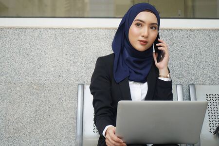 Attractive female muslim woman on a laptop and phoneの写真素材