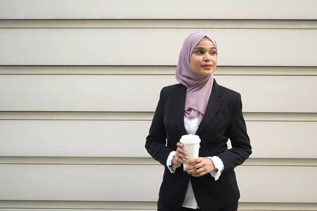 Young asian muslim business woman in head scarf with coffeeの写真素材