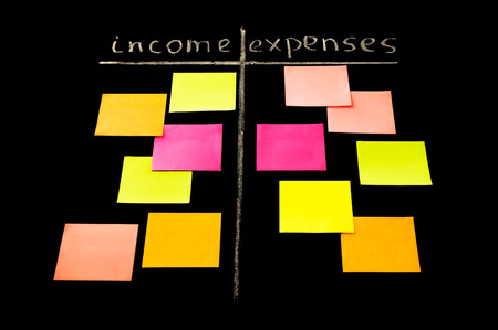 Comparison of income and expenses conceptional drawing on the chalkboard with color sticky notesの写真素材