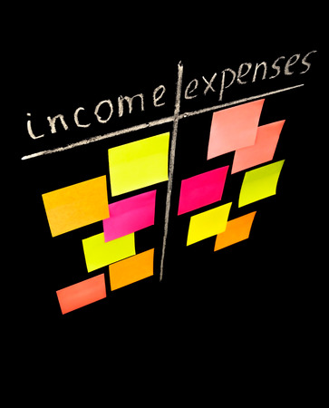 Comparison of income and expenses conceptional drawing on the chalkboard with color sticky notesの写真素材