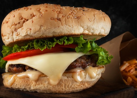 A delicious hamburger with a juicy cutlet, cheese, tomato and salad.の写真素材