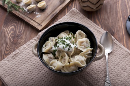 Boiled homemade dumplings with greens and sour creamの写真素材