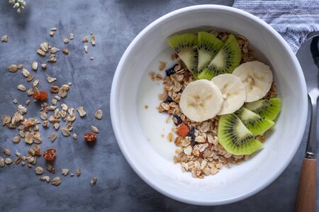 Homemade granola with raisins, dried apricots, nuts, banana, kiwi and yogurtの写真素材