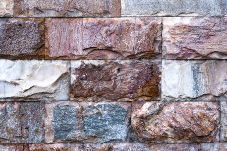 The wall is made of textured marble of different colors. A stone wall with an interesting marble texture. The marble facing of the wall.の写真素材