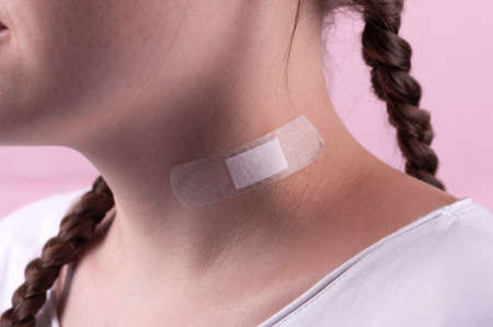 Injury on the neck sealed with a plaster. Providing medical care.の写真素材